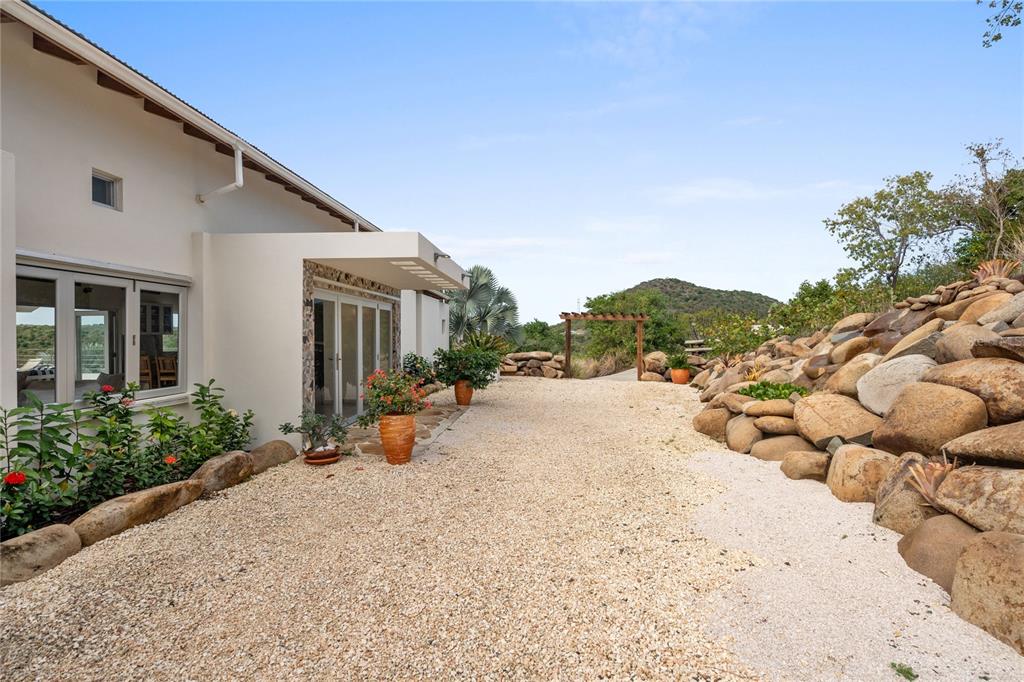 A gravel driveway leads to a modern house exterior with a stone retaining wall — 11 BARRIO FRAILES, CULEBRA, PR
