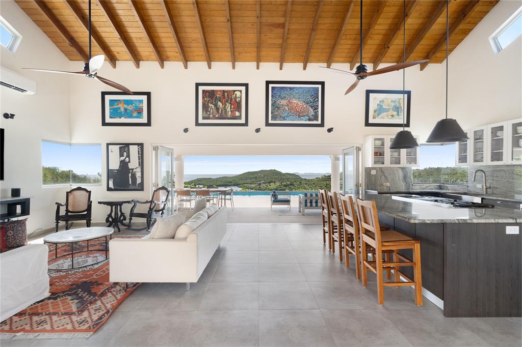 An open-concept living room and kitchen feature a vaulted wood ceiling and panoramic ocean views — 11 BARRIO FRAILES, CULEBRA, PR