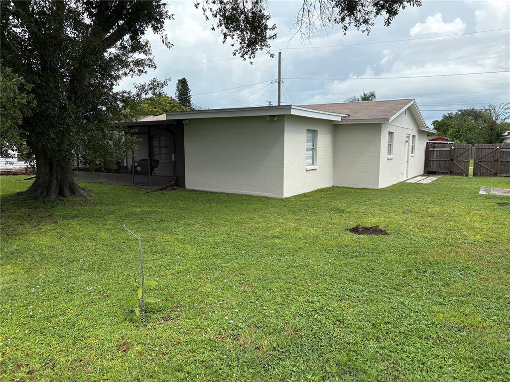 The exterior of a light-colored, single-story house features a screened-in porch and a large tree — 6418 W PARIS STREET, TAMPA, FL