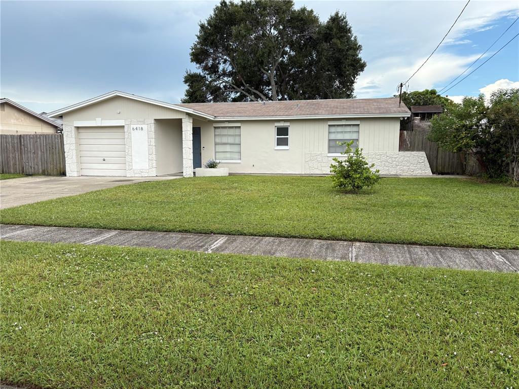 A single-story house with a beige exterior, a one-car garage, and a front lawn — 6418 W PARIS STREET, TAMPA, FL
