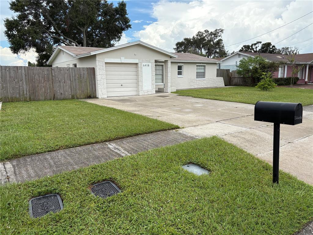 A single-story house with a beige exterior, a one-car garage, and a concrete driveway — 6418 W PARIS STREET, TAMPA, FL