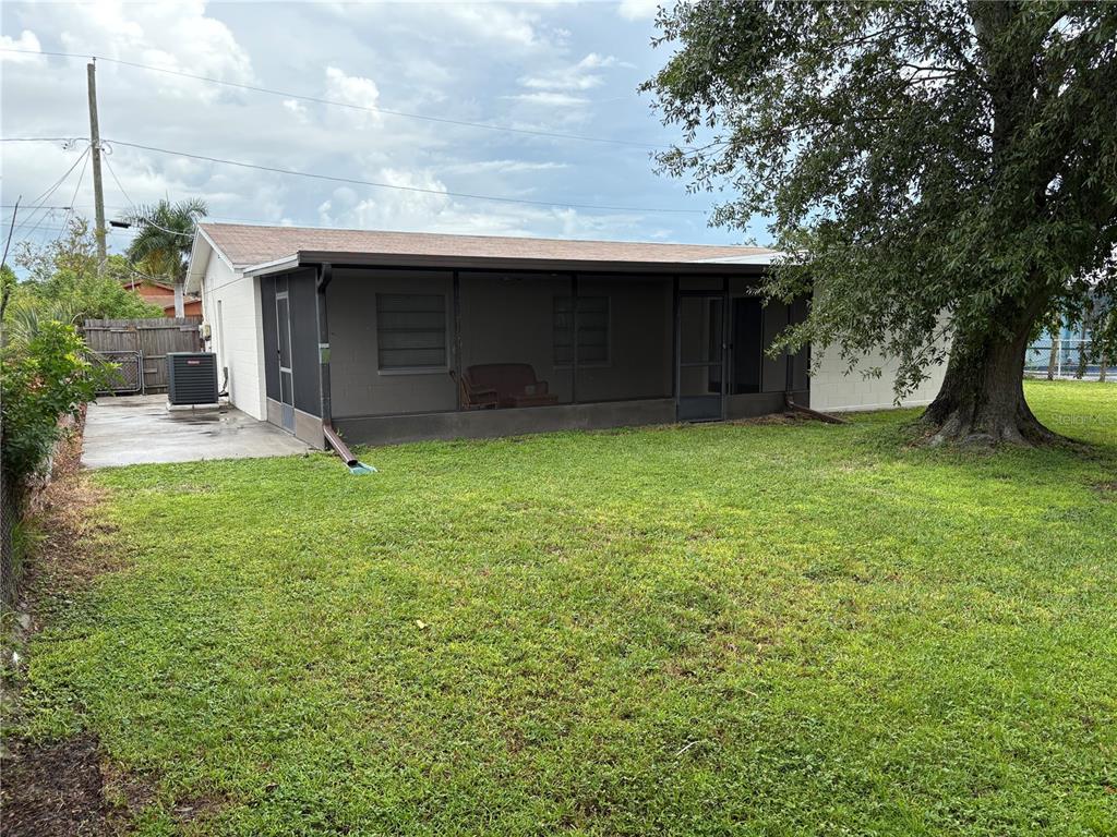 The exterior of a house features a screened-in back porch and a large grassy yard — 6418 W PARIS STREET, TAMPA, FL