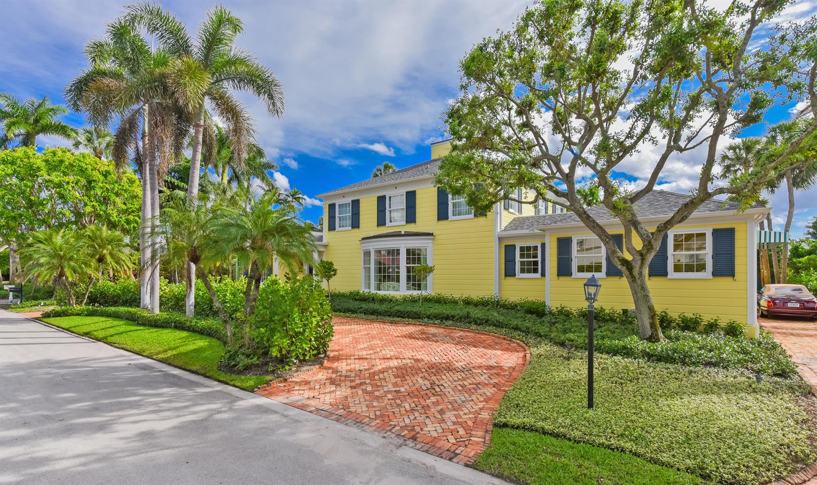 A yellow two-story house with blue shutters features a brick driveway and palm trees — 250 Algoma Road, Palm Beach FL 33480, PALM BEACH, FL