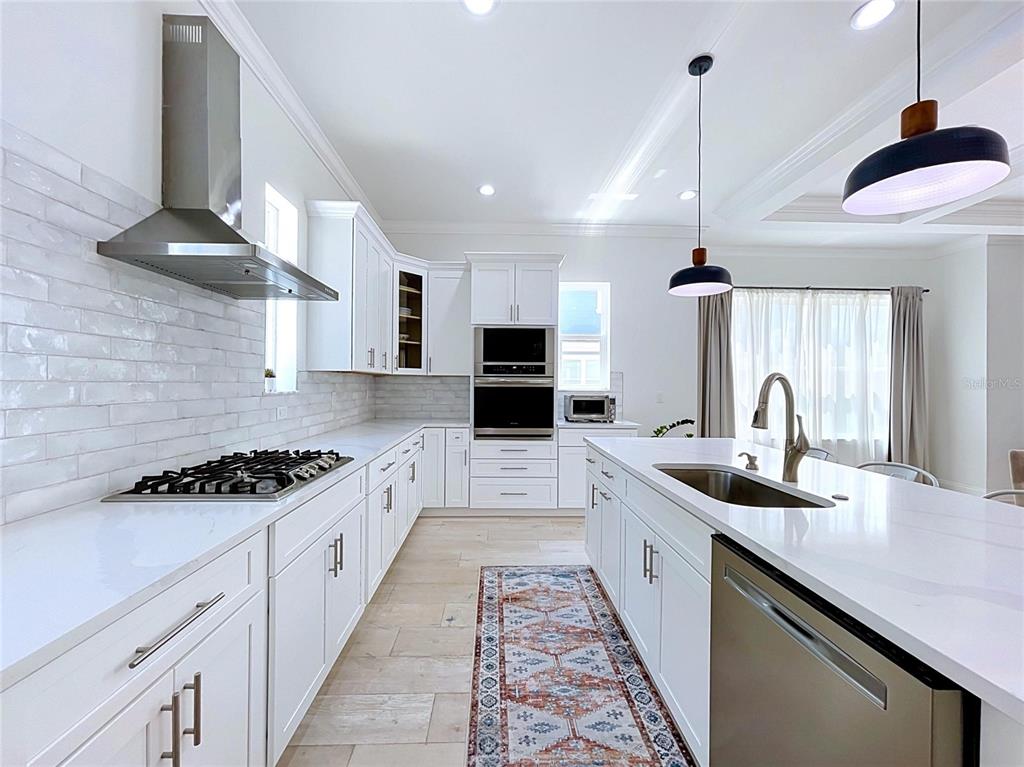 A modern white kitchen features a large island, stainless steel appliances, and a tile backsplash — 3702 W ROLAND STREET UNIT 3, TAMPA, FL