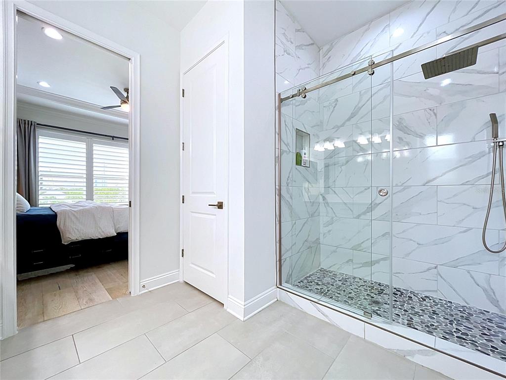 A bathroom features a glass-enclosed walk-in shower with marble-look tile and a pebble floor — 3702 W ROLAND STREET UNIT 3, TAMPA, FL