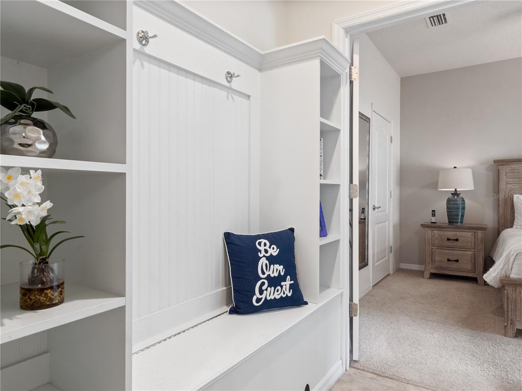 A white built-in mudroom bench with shelving sits in a hallway outside a bedroom — 8867 GENEVE COURT, KISSIMMEE, FL