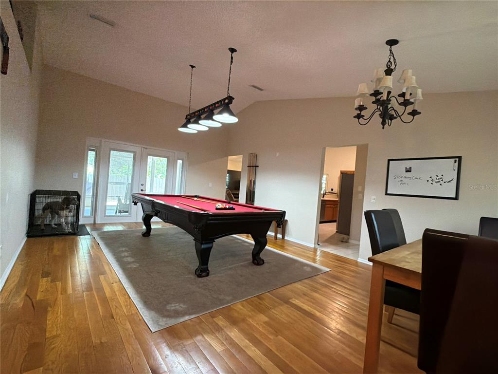 A room features a pool table, a dining set, and hardwood flooring under vaulted ceilings — 503 RAPID FALLS DR, BRANDON, FL