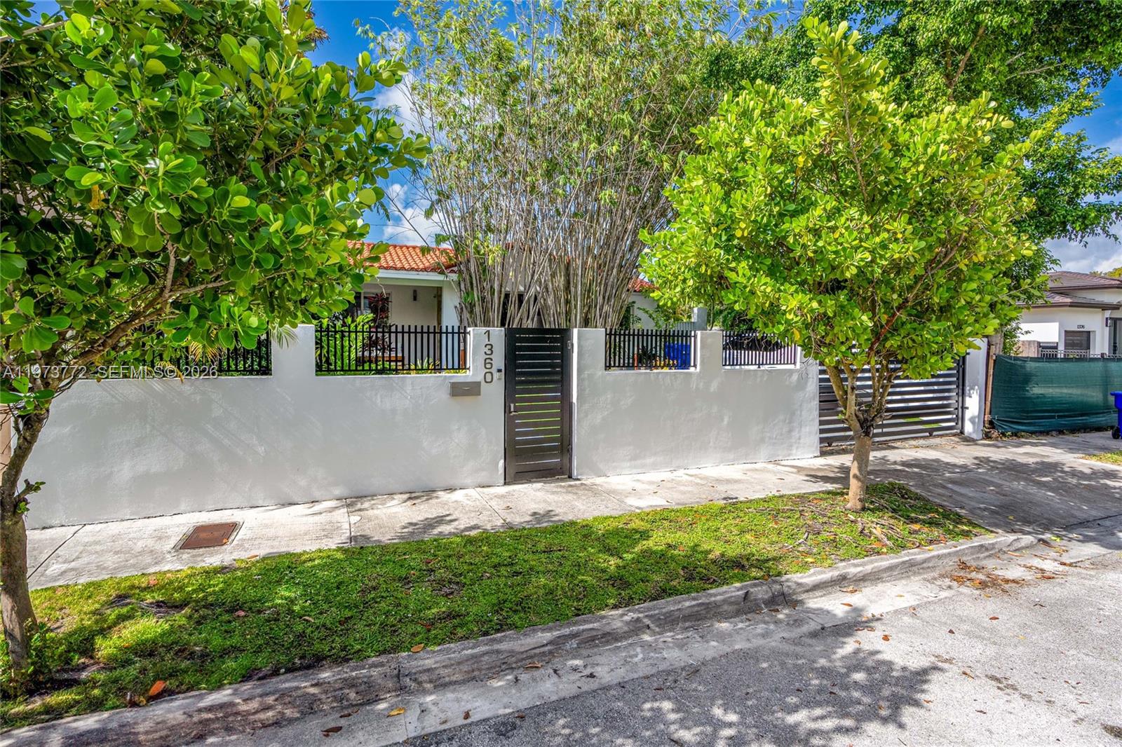 A white stucco wall with a black metal gate and fence surrounds a residential property — 1360 SW 16th St, Miami FL 33145, MIAMI, FL