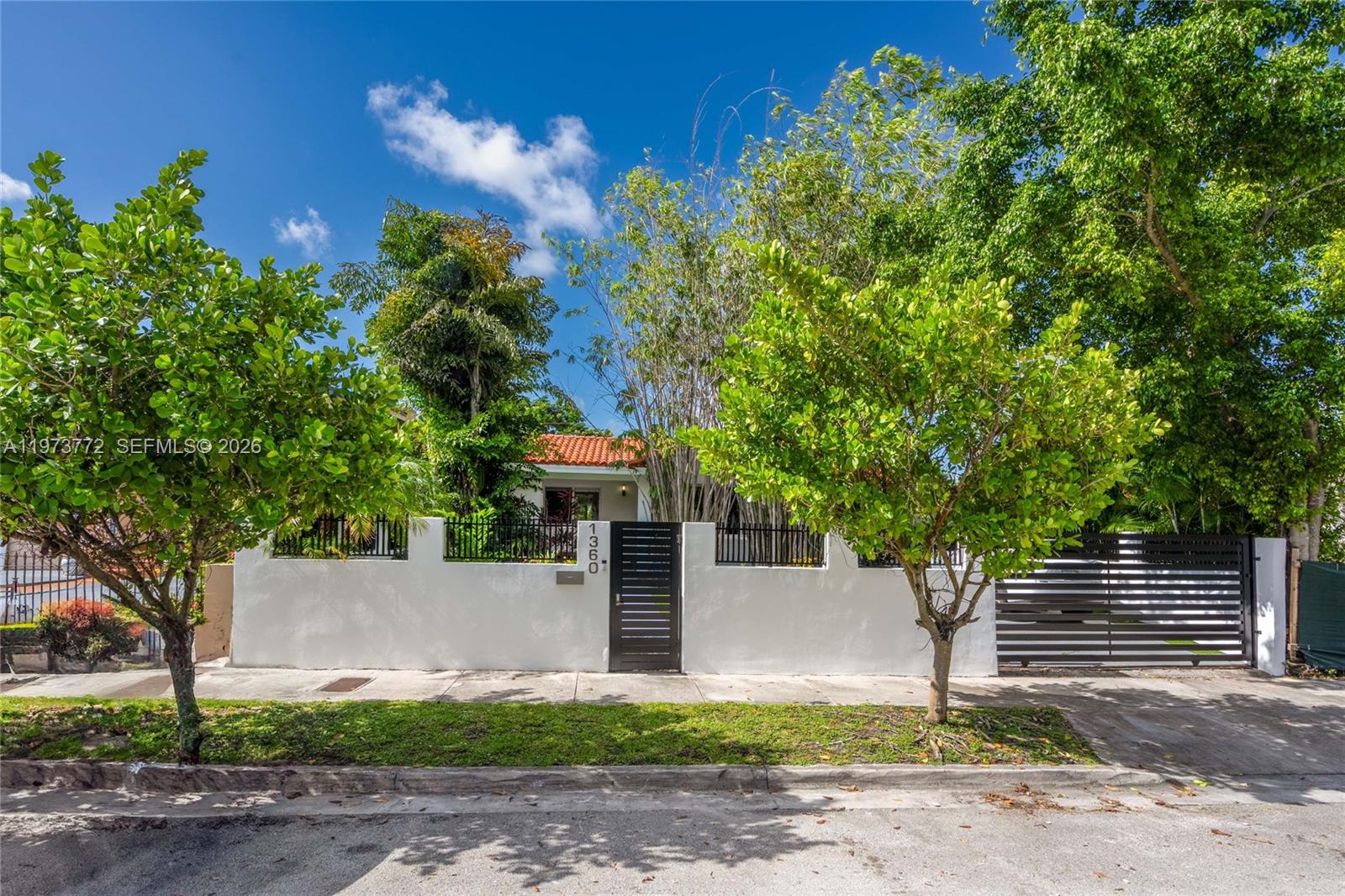 A white stucco wall with a black gate and house number fronts a residential property — 1360 SW 16th St, Miami FL 33145, MIAMI, FL