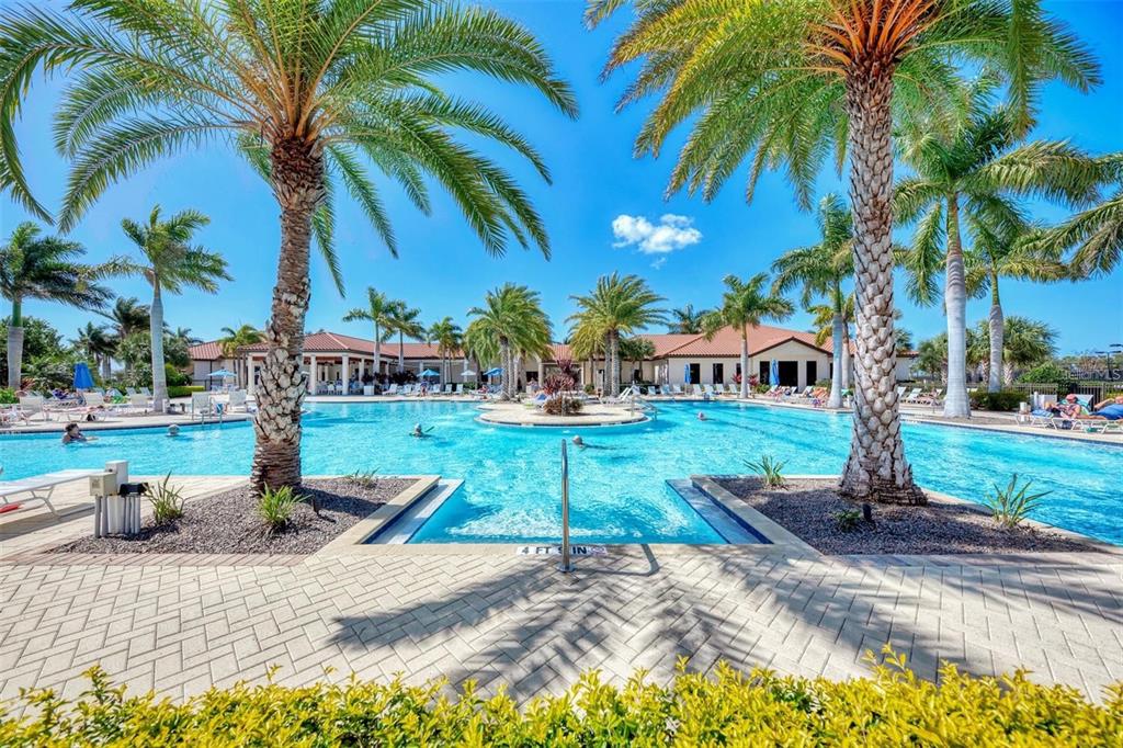 A large outdoor swimming pool surrounded by palm trees and a clubhouse building — 23321 AWABUKI DRIVE UNIT 8-102, VENICE, FL