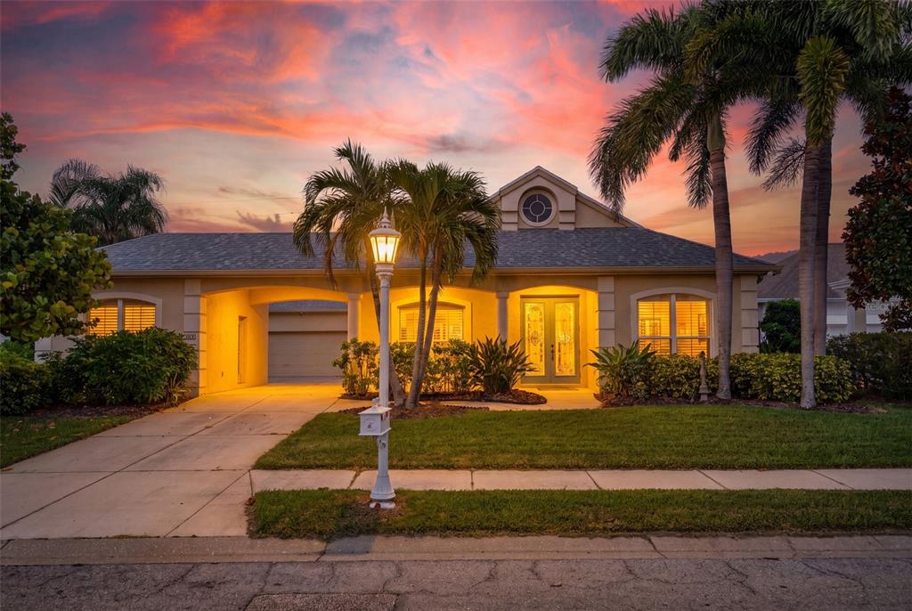 A single-story house with a garage, palm trees, and a mailbox at sunset — 171 AMERICAS CUP BOULEVARD, BRADENTON, FL