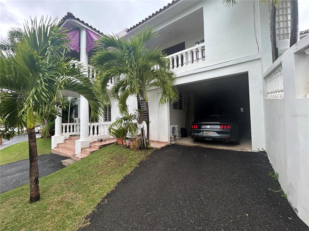 A two-story white house with a covered carport and a parked car — 545 SECTOR TORO, COAMO, PR