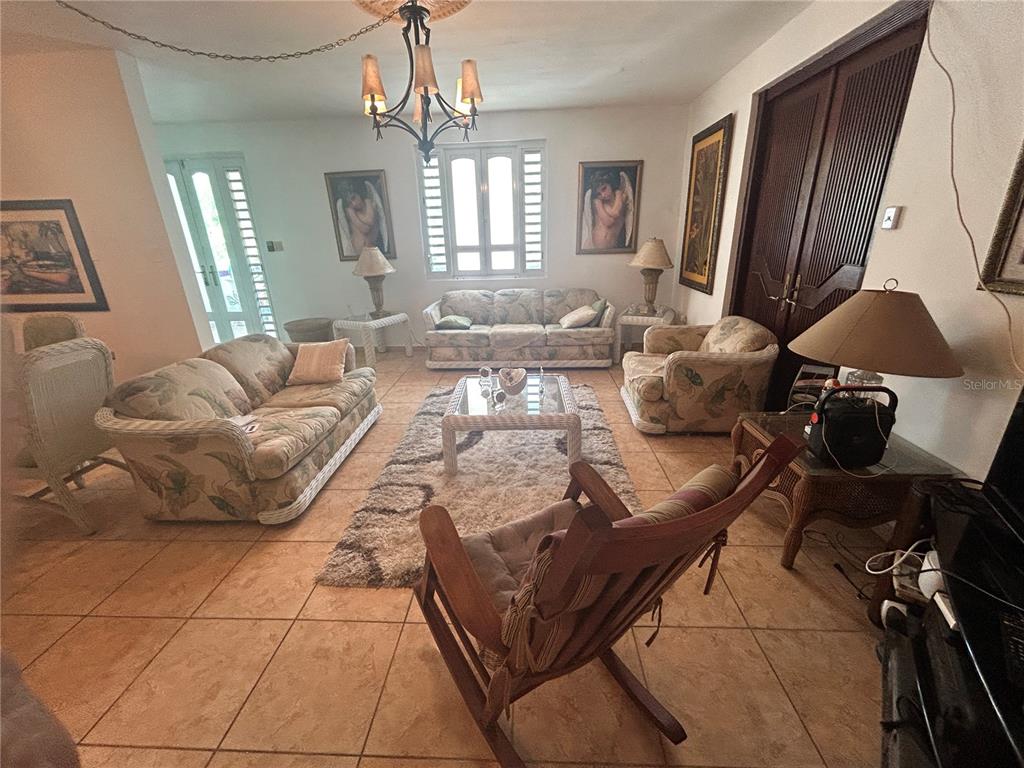 A living room features tile floors, floral-patterned furniture, a central rug, and a chandelier — 545 SECTOR TORO, COAMO, PR