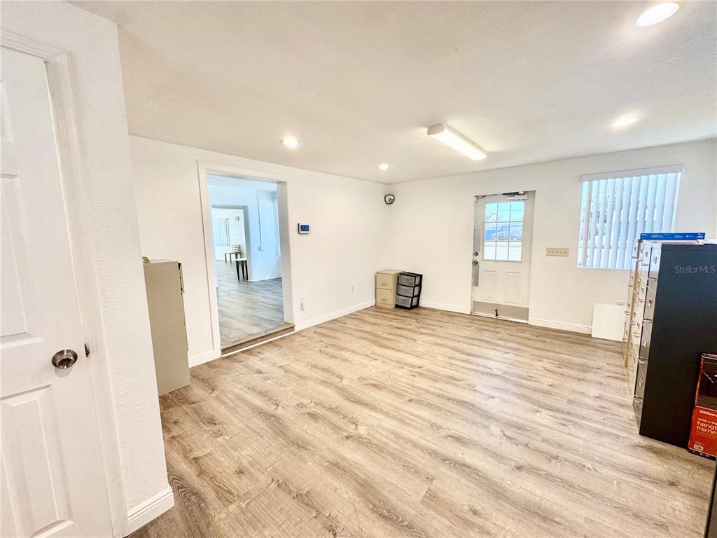 An empty room with light wood-look flooring, white walls, a doorway, and a glass-paneled door — 4795 49TH STREET N, ST PETERSBURG, FL