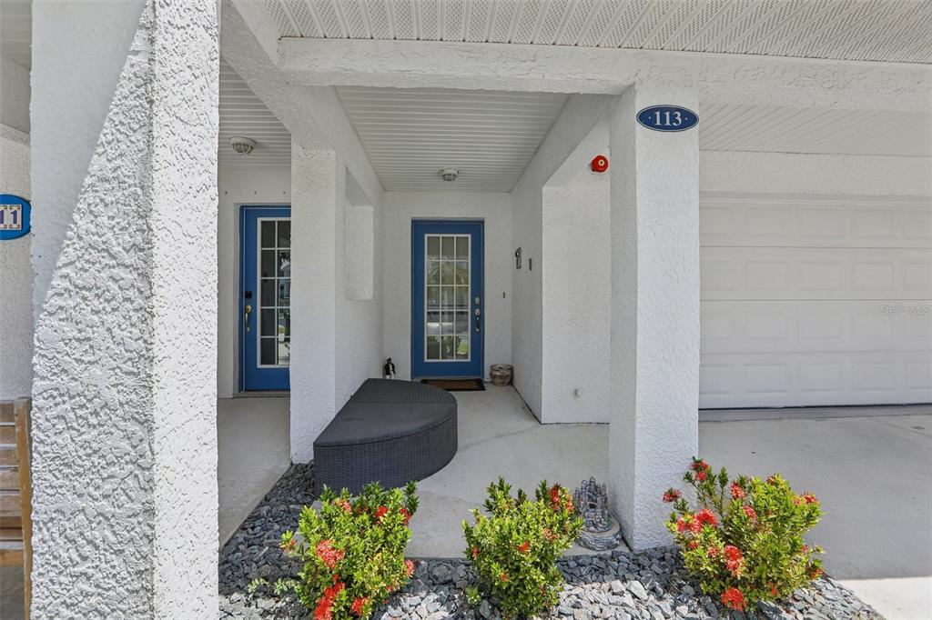 The exterior view shows a covered entryway with a blue door and a garage — 113 YACHT CLUB CIRCLE, NORTH REDINGTON BEACH, FL