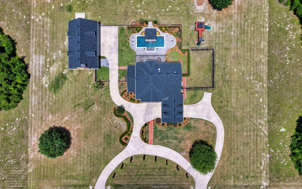An aerial view shows a house with a pool, detached garage, and playground on land — 537 SW WINDSOR DRIVE, LAKE CITY, FL