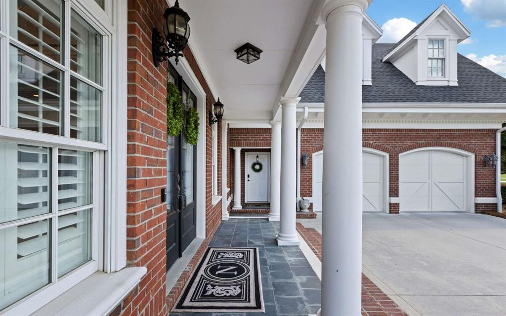 A brick house exterior features a covered porch with white columns and a slate floor — 537 SW WINDSOR DRIVE, LAKE CITY, FL