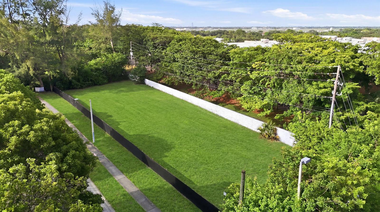 An aerial view shows a rectangular, grass-covered vacant lot enclosed by a fence and trees — 1800 N Sherman Circle, Miramar FL 33025, MIRAMAR, FL