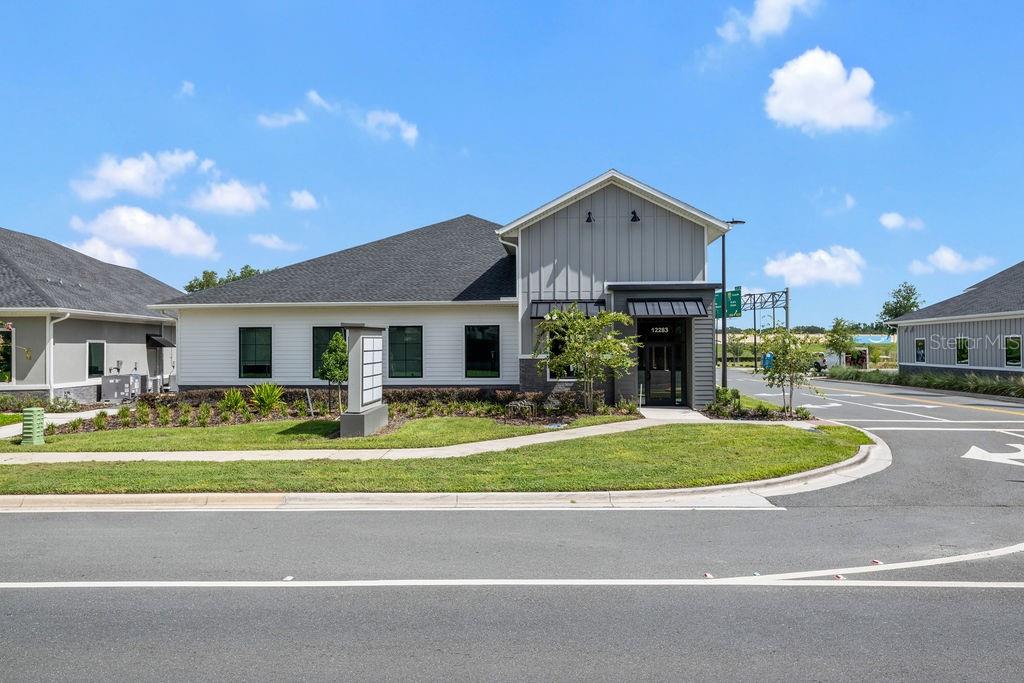 A modern single-story commercial building with white siding and a gray vertical-paneled entryway — 12283 STONEYBROOK WEST PARKWAY UNIT B, WINTER GARDEN, FL