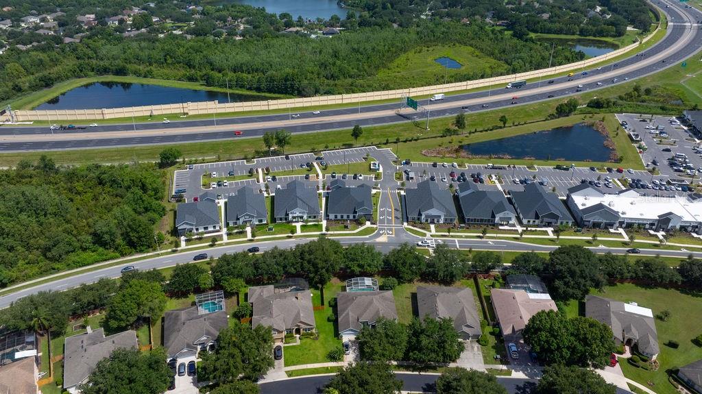 An aerial view shows a suburban neighborhood with houses, a commercial complex, and a highway — 12283 STONEYBROOK WEST PARKWAY UNIT B, WINTER GARDEN, FL