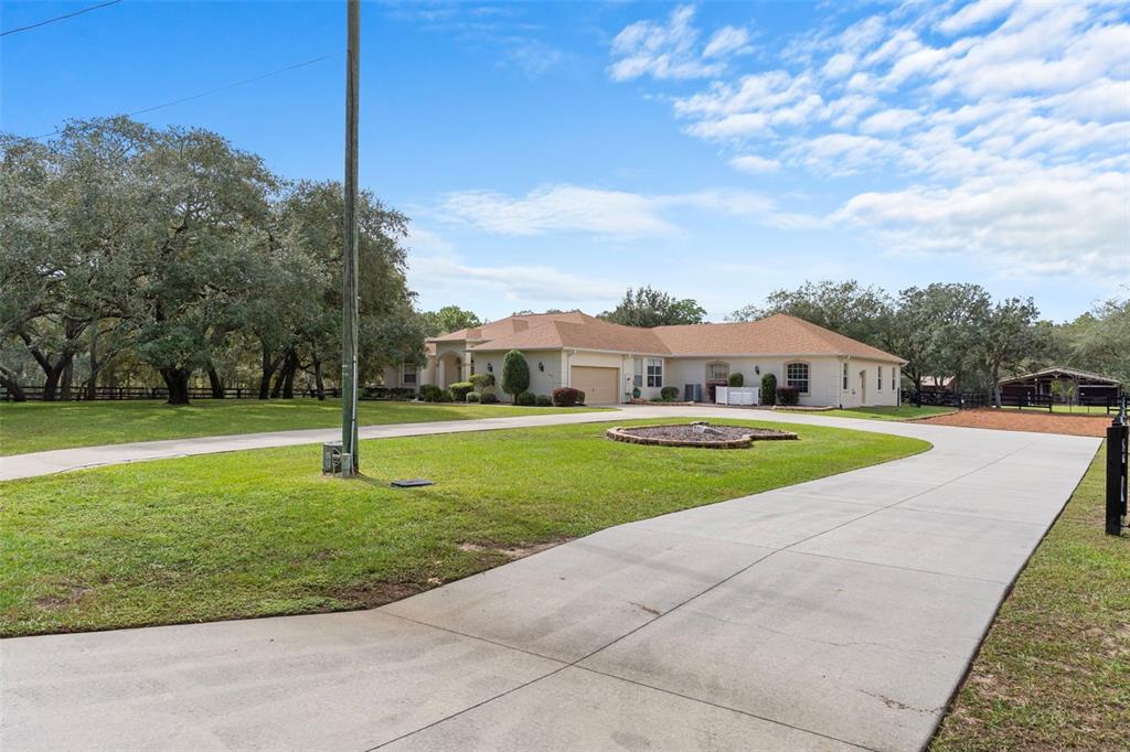 A single-story house with a concrete driveway, a lawn, and a small barn — 4202 N PONY DRIVE, BEVERLY HILLS, FL