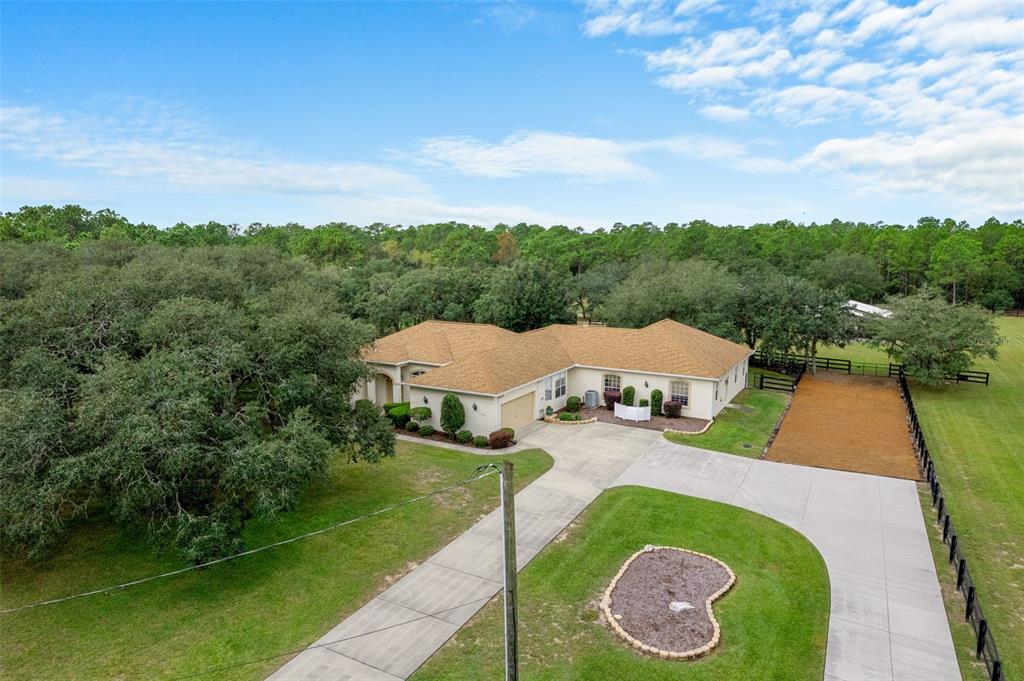 An aerial view shows a single-story house with a tan roof, concrete driveway, and fenced yard — 4202 N PONY DRIVE, BEVERLY HILLS, FL