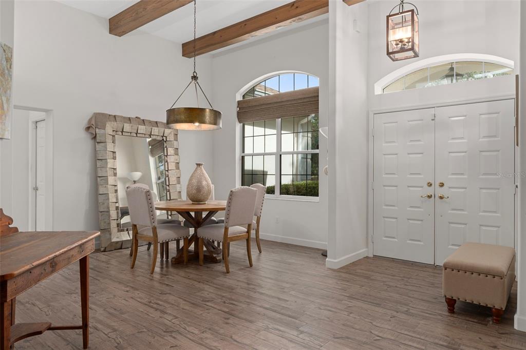 A dining area with wood-look tile floors, exposed ceiling beams, and a large floor mirror — 4202 N PONY DRIVE, BEVERLY HILLS, FL