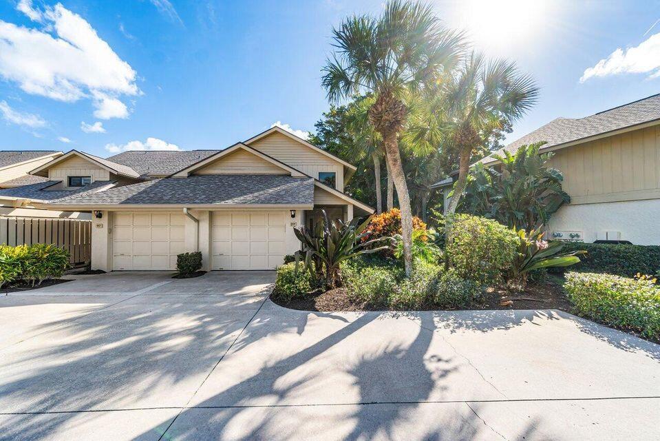 A two-story townhouse with a double garage, concrete driveway, and palm trees in front — 17138 Waterbend Drive # 217, Jupiter FL 33477, JUPITER, FL