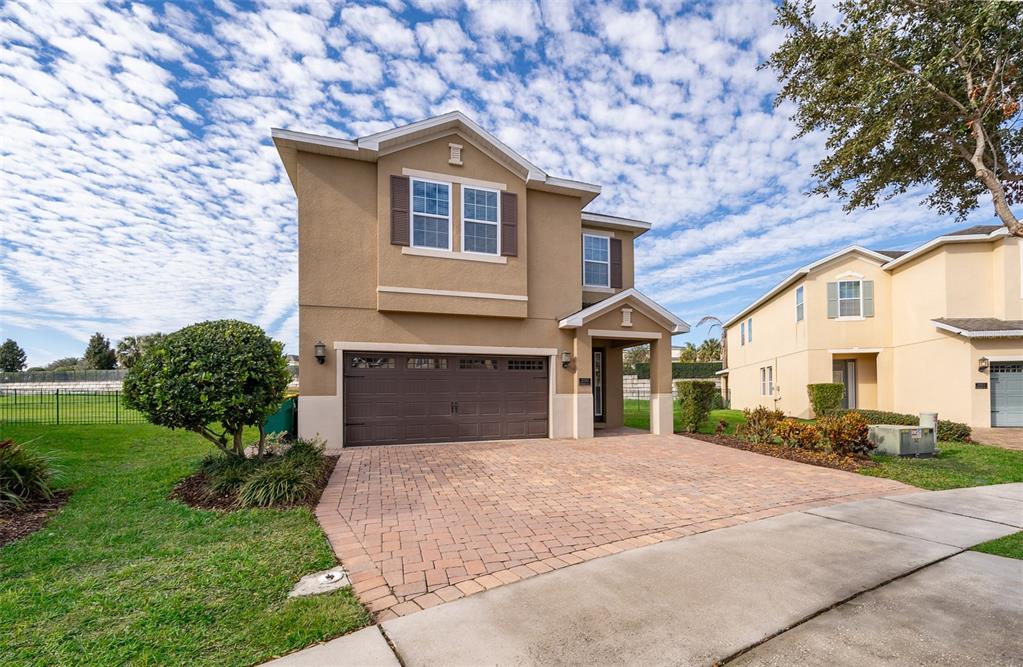 A two-story tan house with a brown garage door and a brick paver driveway — 250 PENDANT COURT, KISSIMMEE, FL