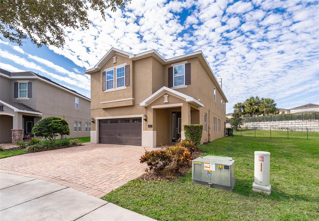 A two-story tan house with a brick driveway and a front-facing garage — 250 PENDANT COURT, KISSIMMEE, FL