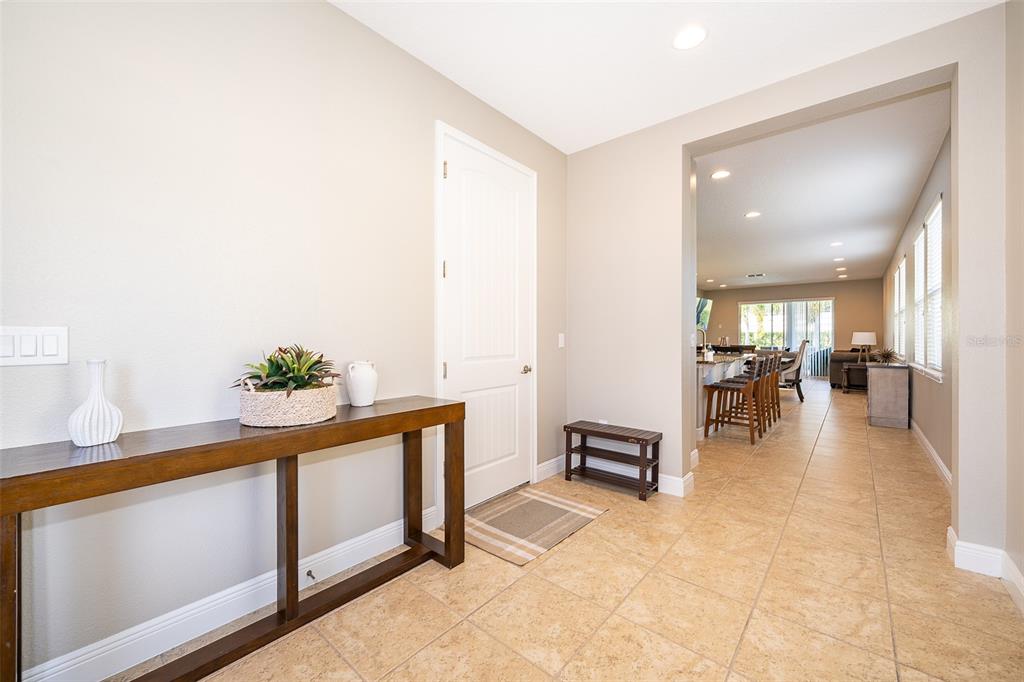 An entryway with tile flooring, a wooden console table, and a view into the kitchen — 250 PENDANT COURT, KISSIMMEE, FL