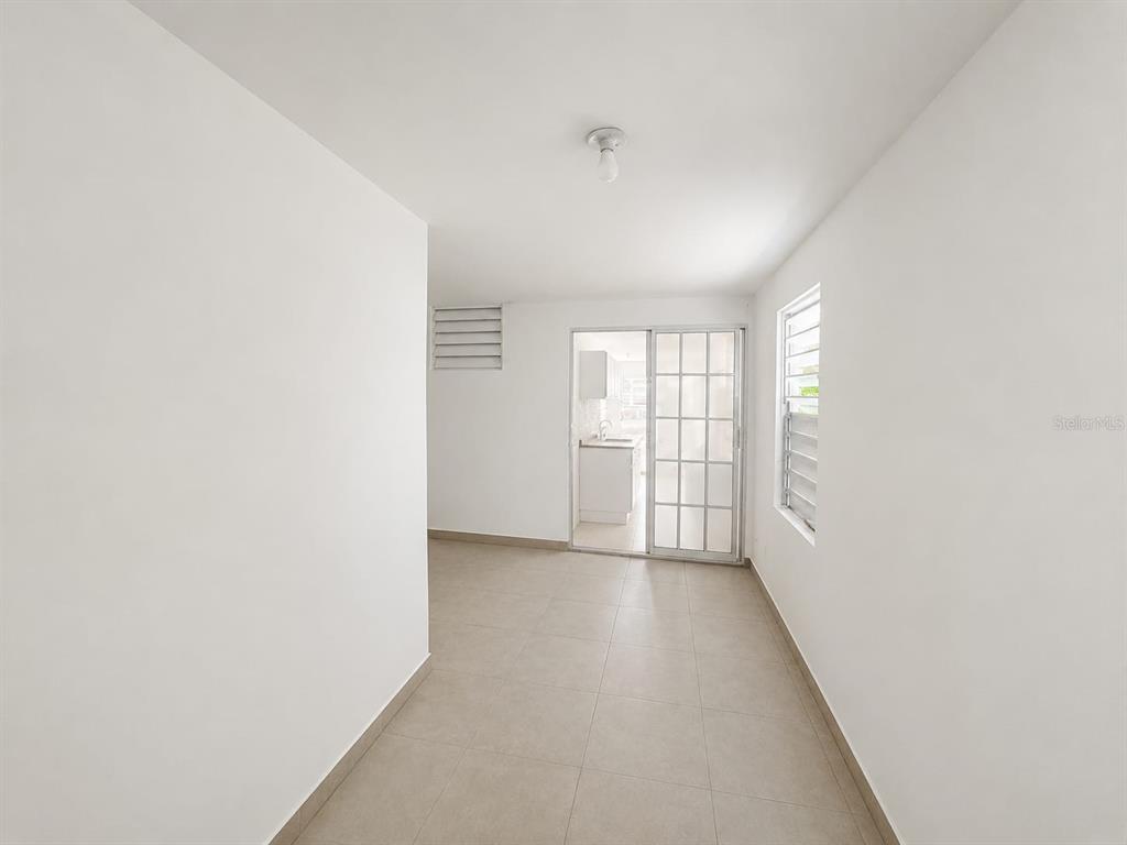 A room with white walls, tile flooring, a sliding glass door, and a window — A1A CALLE A  URB. LOS ANGELES, YABUCOA, PR