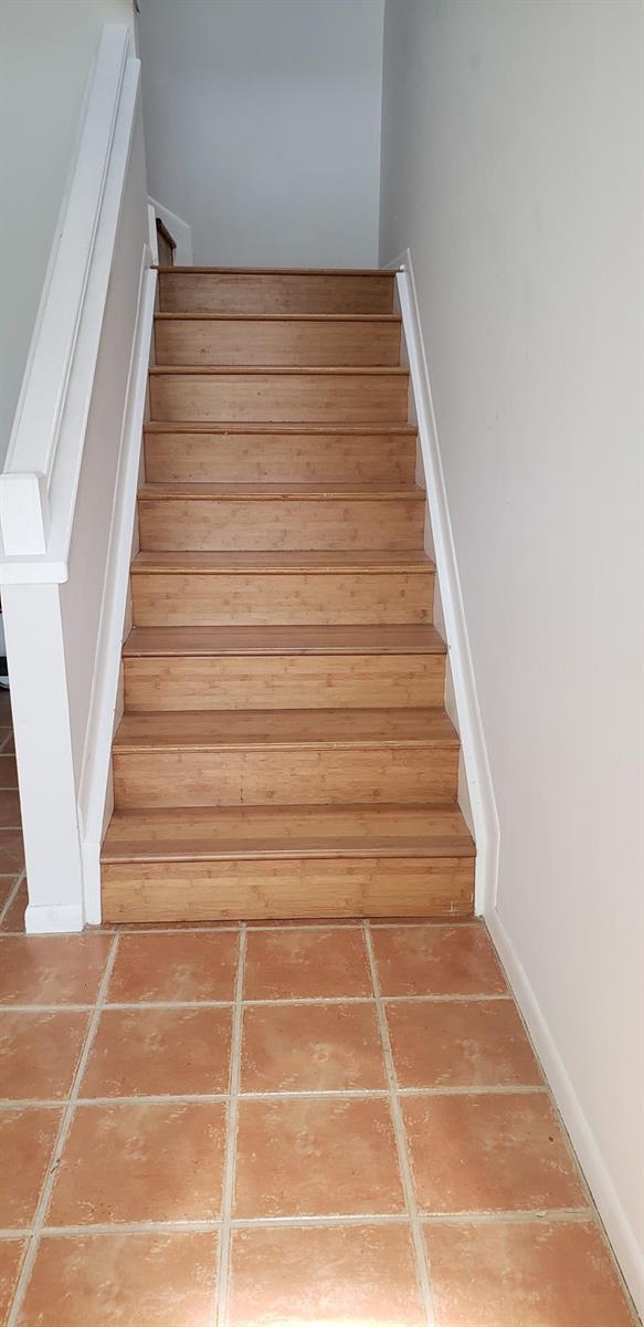 A staircase with bamboo treads leads upward between white walls above a tiled floor — 5326 Buckhead Circle # 2010, Boca Raton FL 33486, BOCA RATON, FL