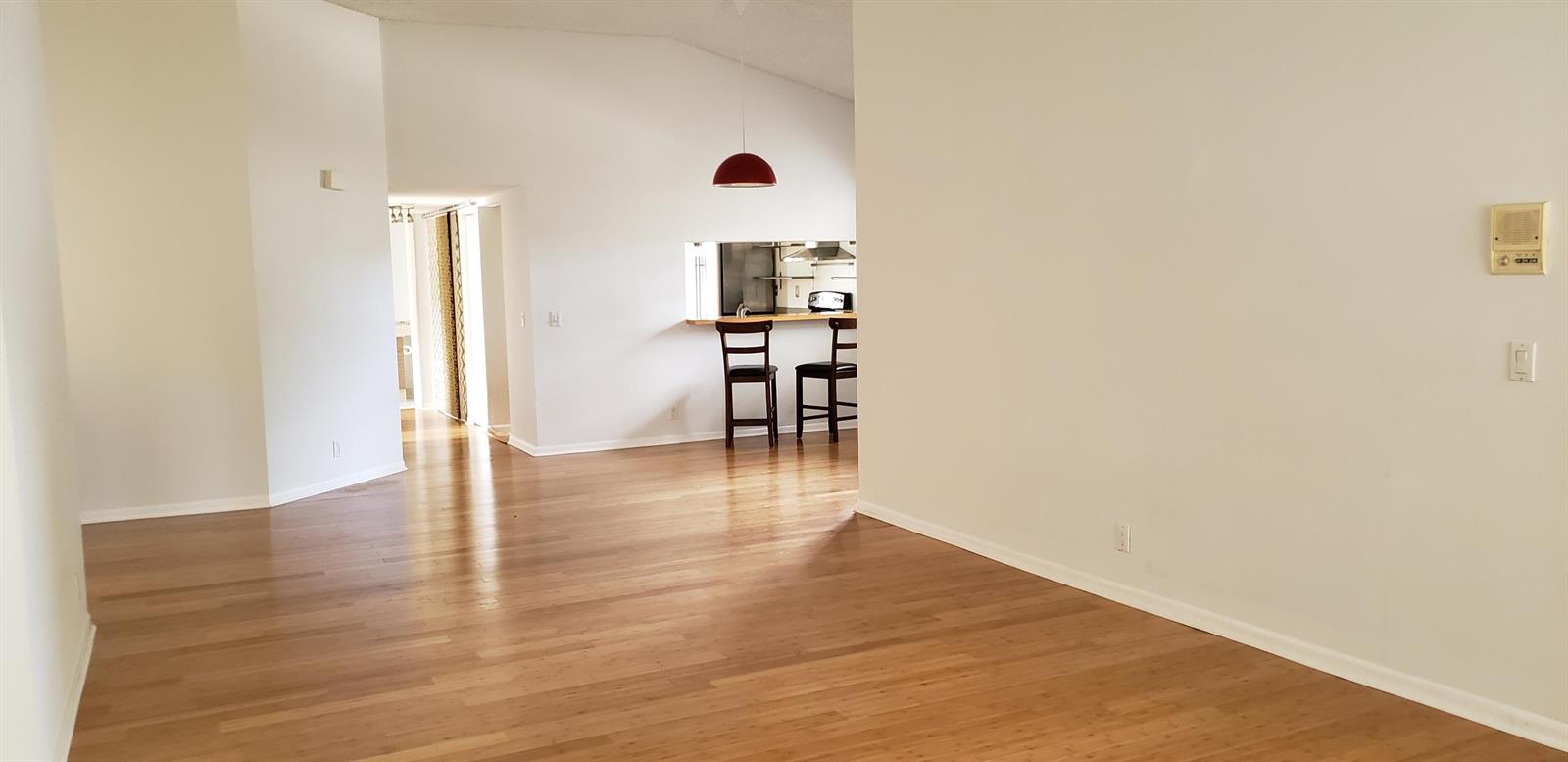 A bright living area features light wood flooring, white walls, and a kitchen breakfast bar — 5326 Buckhead Circle # 2010, Boca Raton FL 33486, BOCA RATON, FL