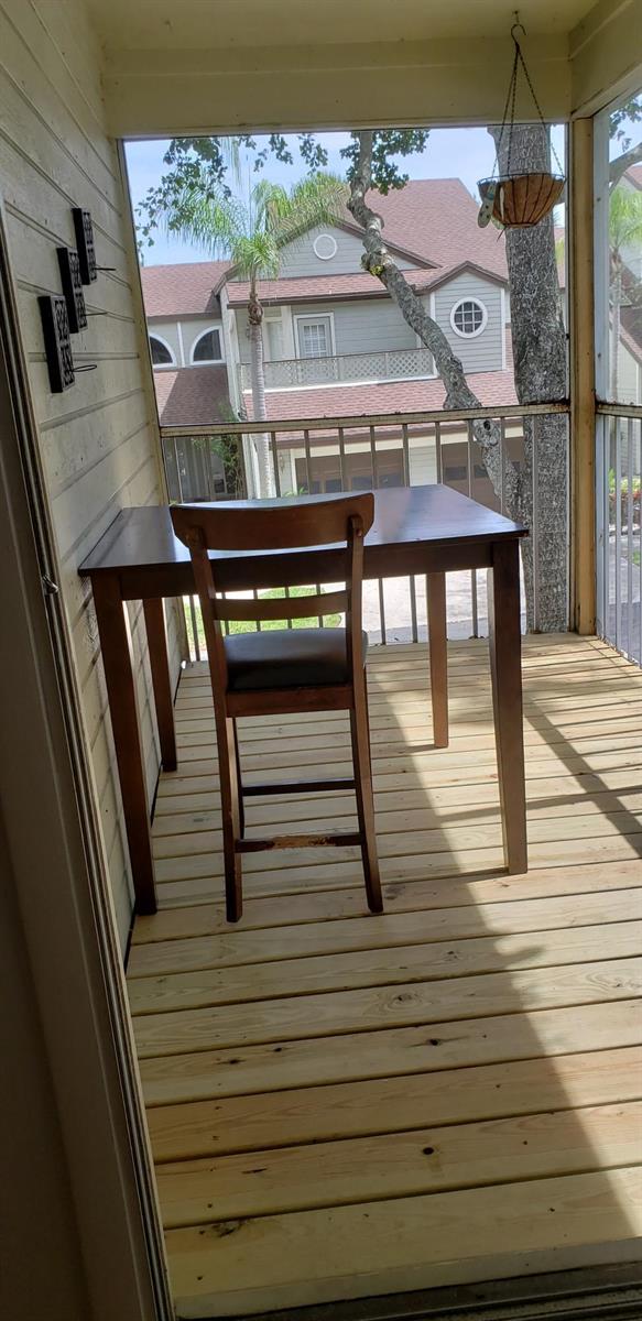 A wooden table and chair sit on a screened-in porch with light wood decking — 5326 Buckhead Circle # 2010, Boca Raton FL 33486, BOCA RATON, FL