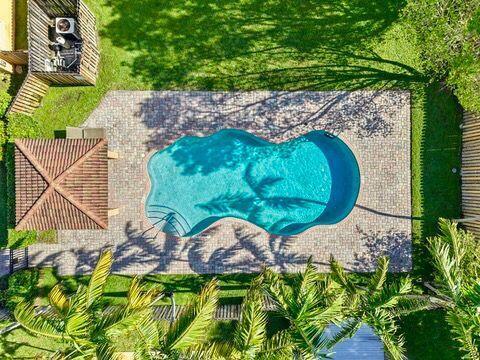 An aerial view shows a curved swimming pool surrounded by a brick patio and palm trees — 330 SW 2nd Avenue # 14, Hallandale Beach FL 33009, HALLANDALE BEACH, FL