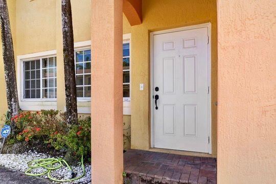 A white front door is set in a peach-colored stucco wall next to a window — 330 SW 2nd Avenue # 14, Hallandale Beach FL 33009, HALLANDALE BEACH, FL