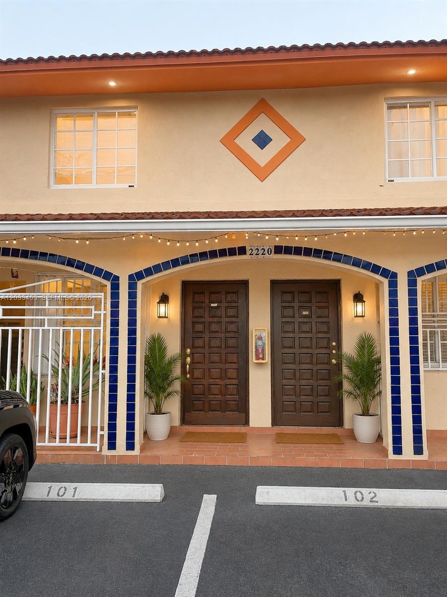 The exterior of a two-story building features two dark wooden entry doors and parking spaces — 2220 W 74th St # 16, Hialeah FL 33016, HIALEAH, FL