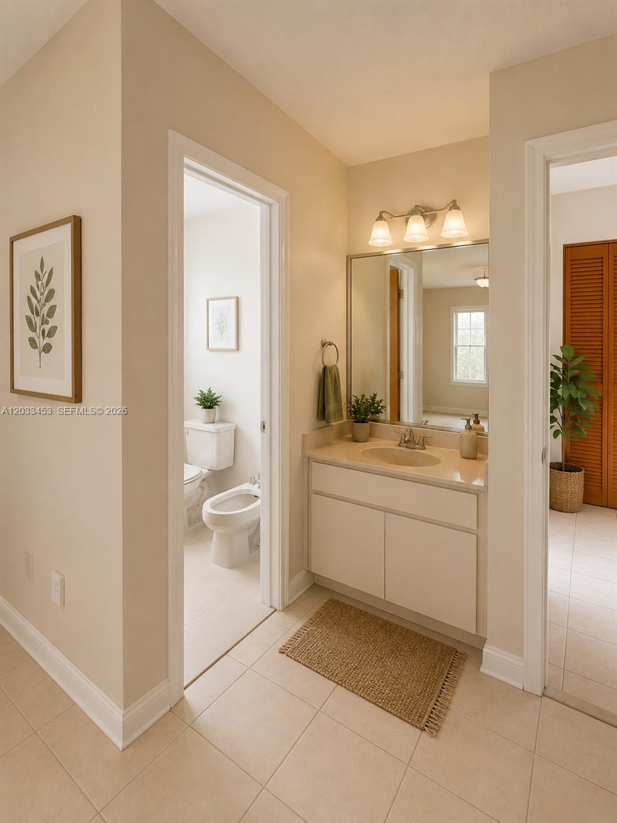 A bathroom features a vanity with a mirror, a separate toilet area, and beige tile flooring — 2220 W 74th St # 16, Hialeah FL 33016, HIALEAH, FL