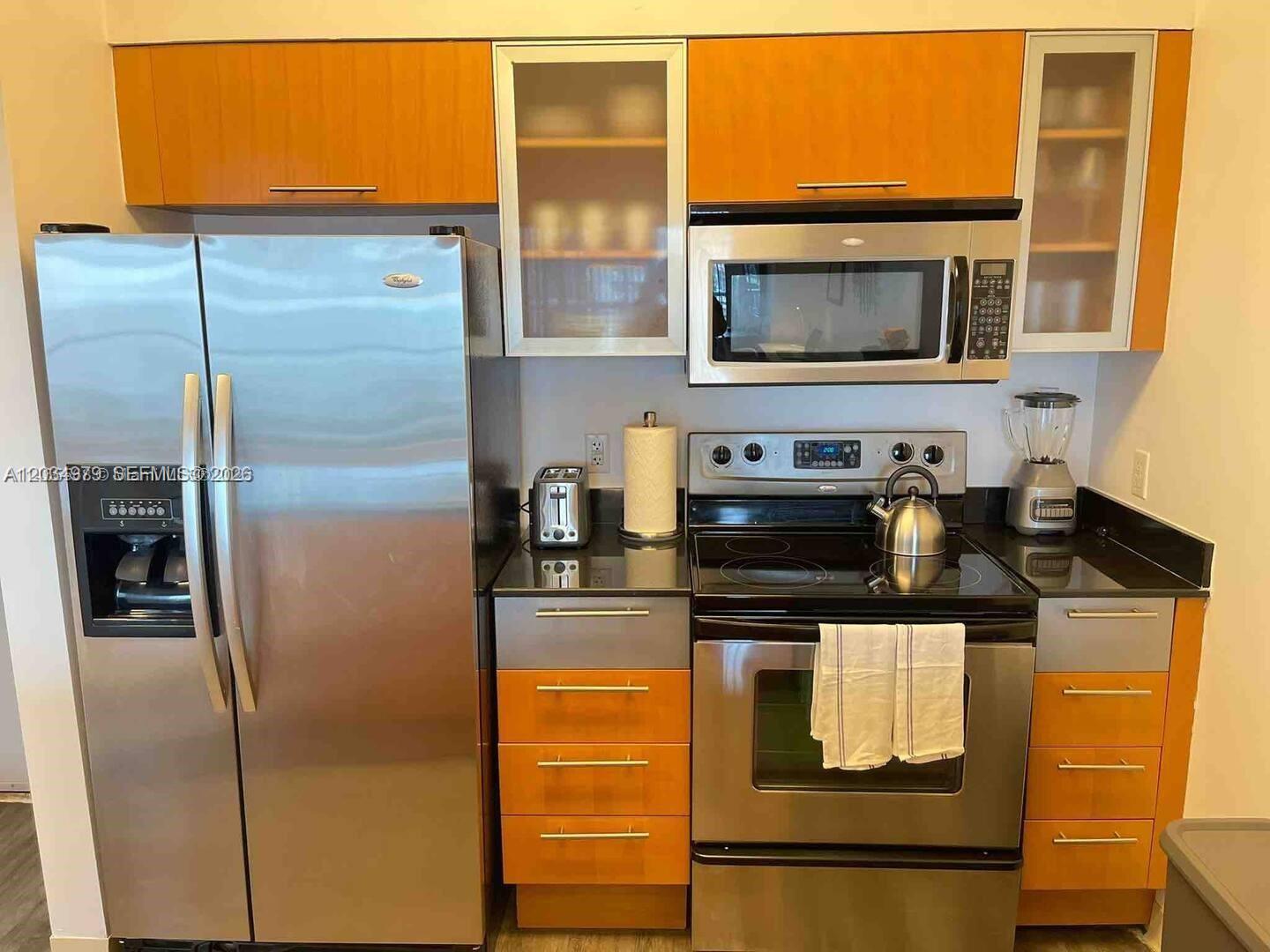 A kitchen features stainless steel appliances, orange cabinetry, and dark countertops — 1750 N Bayshore Dr # 3010, Miami FL 33132, MIAMI, FL