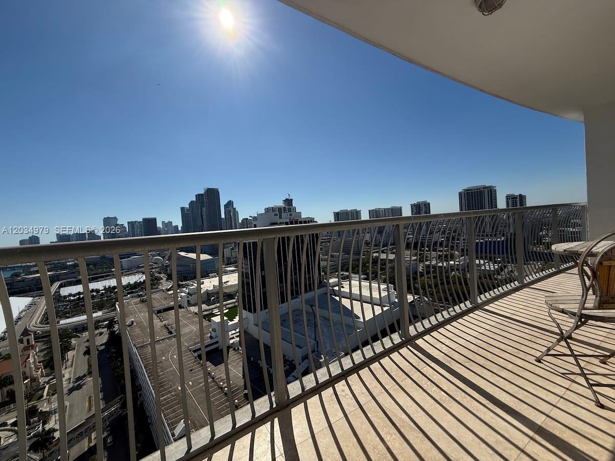 A high-rise balcony with metal railings overlooks a city skyline and a parking lot — 1750 N Bayshore Dr # 3010, Miami FL 33132, MIAMI, FL