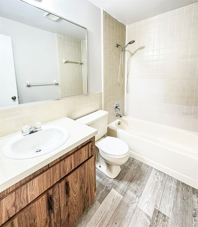 A bathroom features a wood-look vanity, a white toilet, and a tub-shower combination — 585 N SCENIC HIGHWAY UNIT 585, BABSON PARK, FL