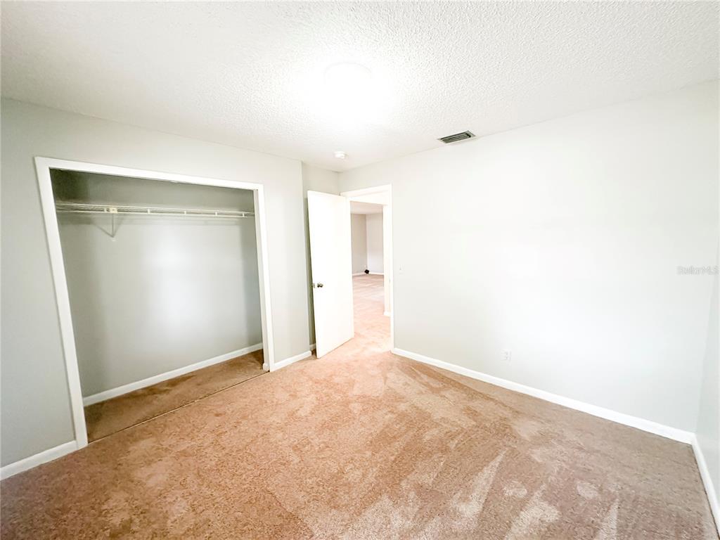An empty bedroom features beige carpet, light gray walls, a closet, and an open doorway — 585 N SCENIC HIGHWAY UNIT 585, BABSON PARK, FL