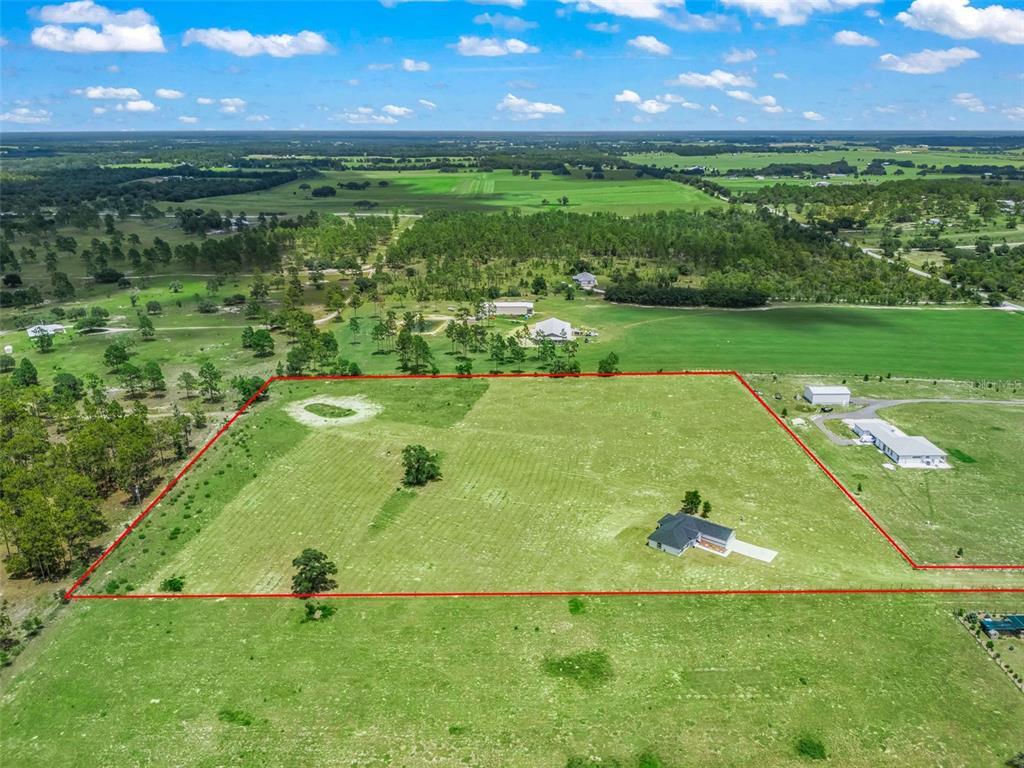An aerial view shows a house situated on a large, fenced-in grassy field — 14461 SE 80TH STREET, MORRISTON, FL