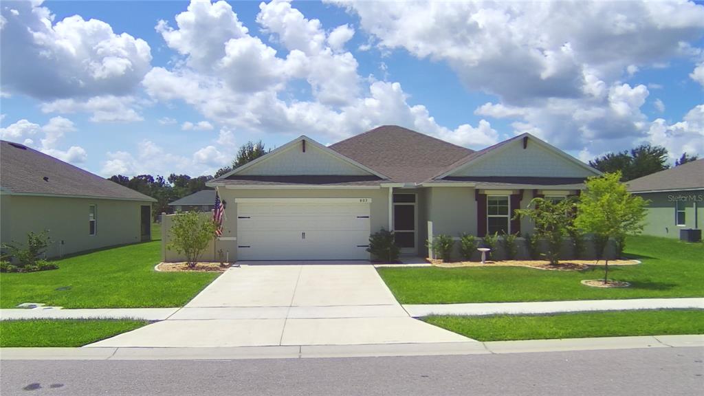 A single-story suburban house with a two-car garage, concrete driveway, and a green lawn — 803 AUBURN GROVE COURT, AUBURNDALE, FL
