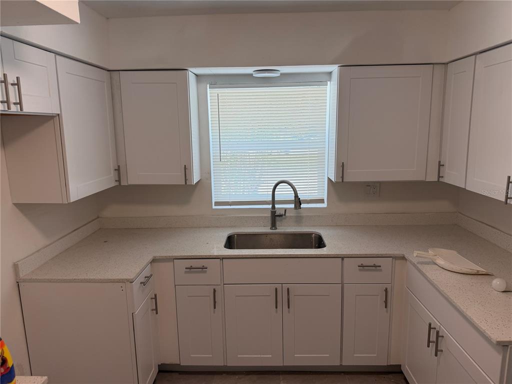 A kitchen features white cabinets, a stainless steel sink, and light-colored countertops — 1405 EDEN DRIVE, INVERNESS, FL
