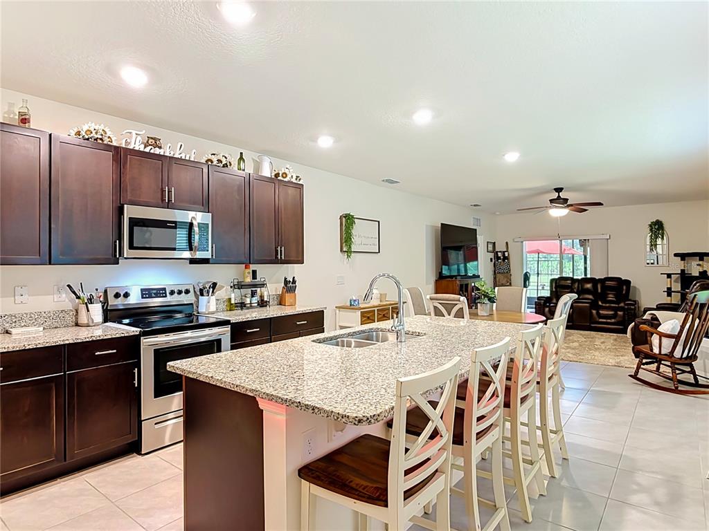 A kitchen with dark wood cabinets, granite countertops, and an island with bar seating — 204 CARYOTA COURT, NEW SMYRNA BEACH, FL