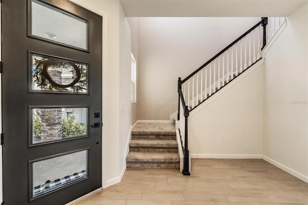 An entryway features a black front door, carpeted stairs, and light-colored wood-look flooring — 6276 GOLDEN BEACH DRIVE, APOLLO BEACH, FL