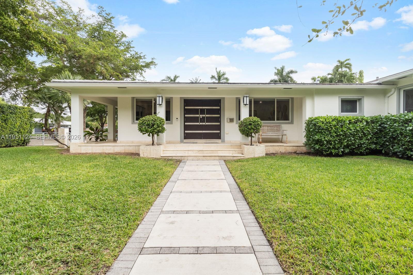 A single-story house features a paved walkway leading to a covered entryway with double doors — 5601 Maggiore St, Coral Gables FL 33146, CORAL GABLES, FL
