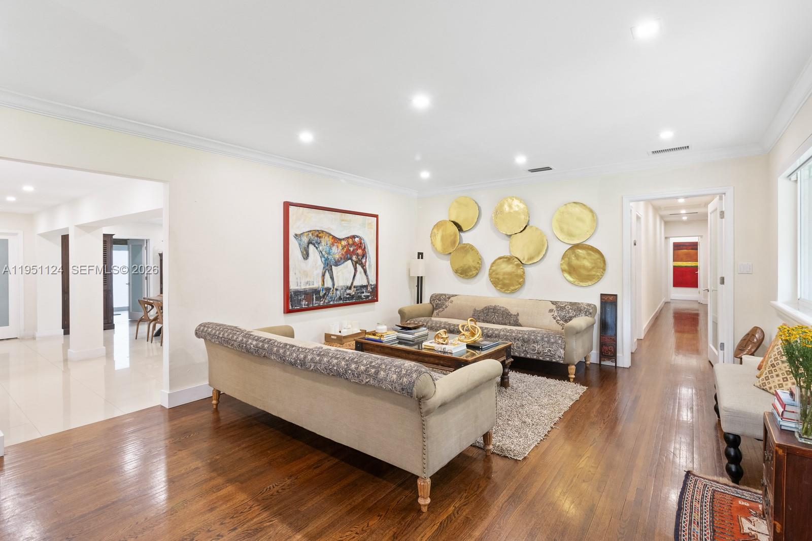 A living room features two sofas, a coffee table, and gold wall art on hardwood floors — 5601 Maggiore St, Coral Gables FL 33146, CORAL GABLES, FL